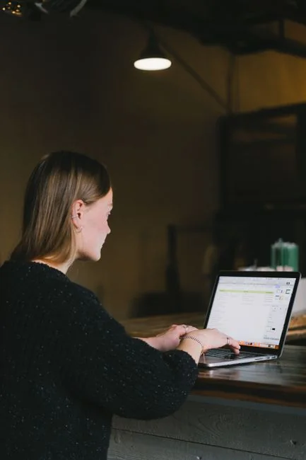 A woman examining a brand strategy document on a clipboard next to a laptop in an office setting.